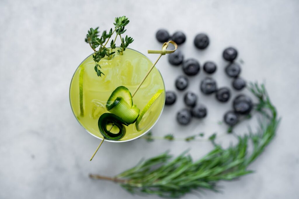 A cocktail with blueberries and herbs on a white background