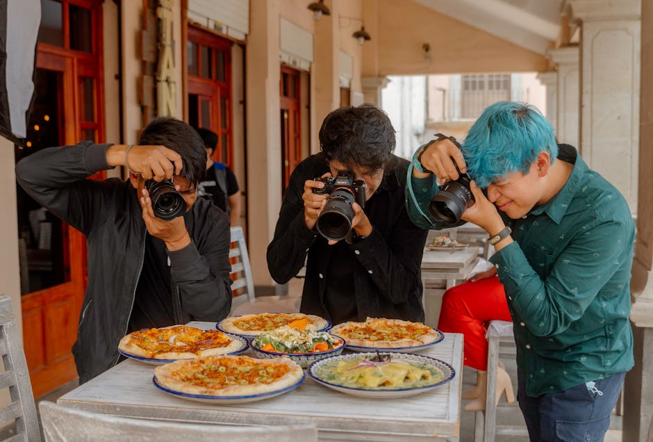 Three photographers taking pictures of a variety of pizzas at an outdoor restaurant in Lerma, Mexico.