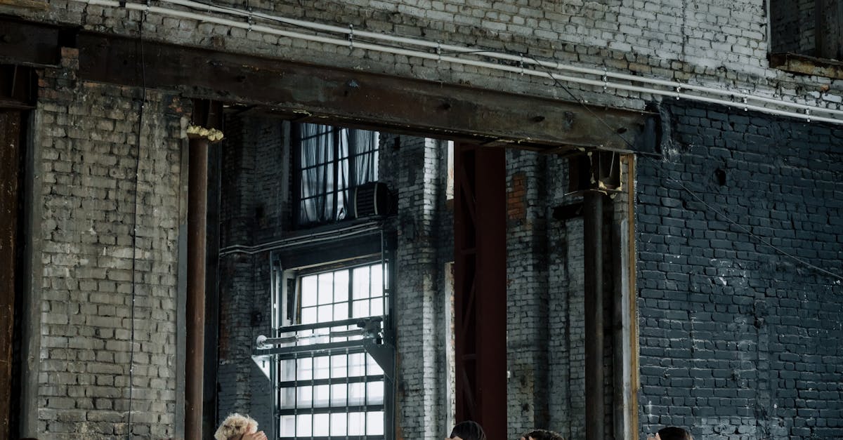 A group of people in white uniforms stand in a line indoors, industrial background.